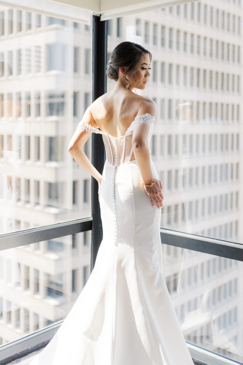A bride posing against the window after putting on her wedding dress for the first time at W Seattle Hotel.