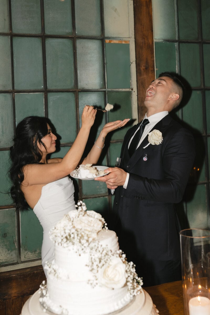 A wedding couple feeding each other a piece of cake after their cake cutting at their Sodo Park Seattle wedding.